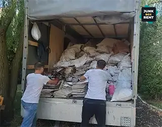 Stacking waste bags in truck.